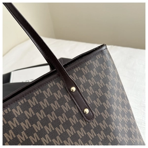 Macro view of brown monogram tote bag with leather trim and gold rivet hardware