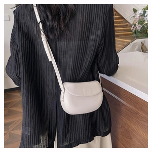 Beige leather saddle bag shown on a model in a casual setting for a stylish daily look