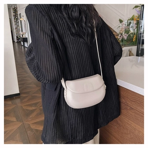 Minimalist cream crescent crossbody bag shown from behind to highlight size and fit
