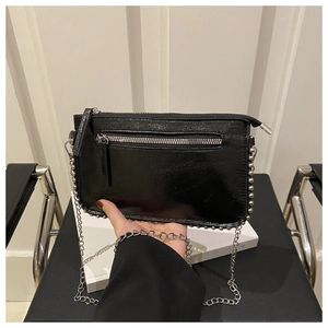 Detail of glossy black chain bag with silver beaded trim and exterior zipper pocket