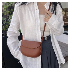 Detail of dark brown faux leather saddle bag with matte finish and crossbody strap