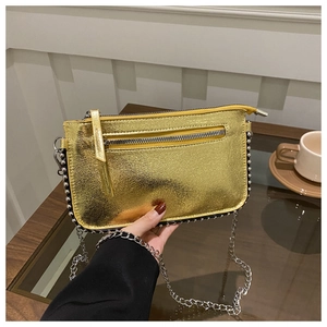 Detail of a shiny gold metallic shoulder bag with silver studs and elegant chain strap