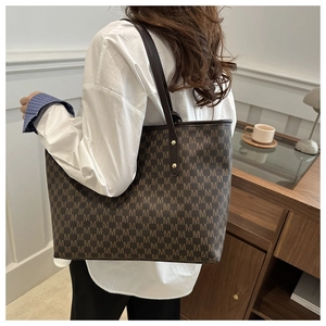 Macro view of canvas tote bag showing vintage M-letter patterns and leather handles