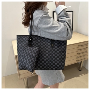 Side view of fashionable black tote bag with gray letter pattern on model in home setting