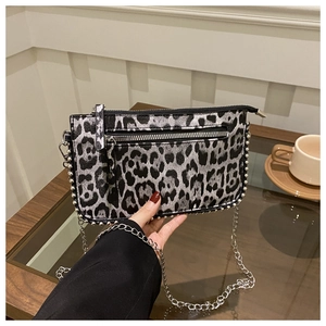 Detail of leopard print bag with silver studs and metal chain in a cafe setting