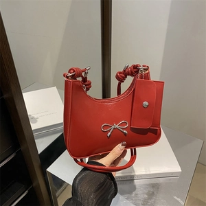 Red bow shoulder bag with glossy finish and matching coin purse in a stylish hand-held pose