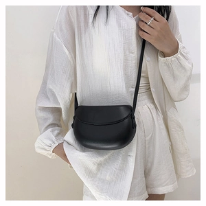 Minimalist black curved saddle bag with matte leather finish shown on model's shoulder