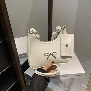Cream hobo bag with metal bow detail and thick braided handle for stylish shoulder wear