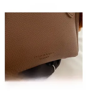 Detail shot of brown lychee grain leather bucket bag with embossed fashion text