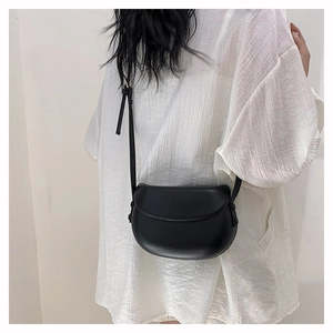 Minimalist black semi-circle saddle bag with sleek matte finish and leather strap