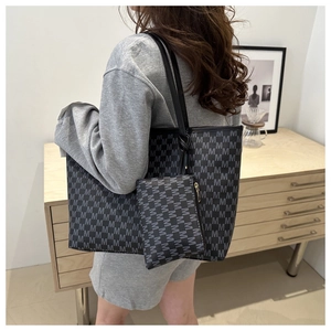 Macro shot of large monogram tote bag with matching zippered pouch on neutral background