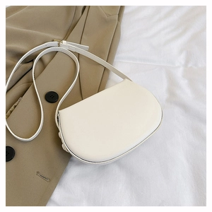 Detail of a minimalist cream-white saddle bag with smooth PU leather and metal buckle strap
