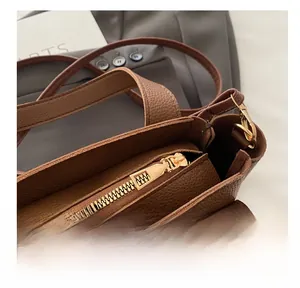 Detail of smooth gold zipper on brown lychee texture leather bucket bag with quality hardware
