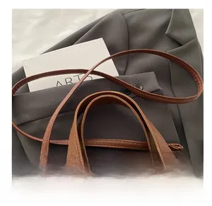 Detail of brown litchi pattern leather bucket bag with golden hardware and adjustable strap