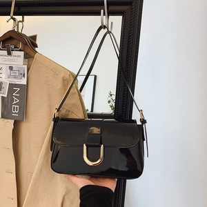 Glossy black patent leather shoulder bag with gold horseshoe buckle and retro design