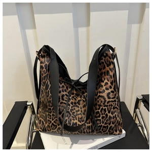 Détail du sac hobo léopard avec bandoulière large sur une surface synthétique brillante