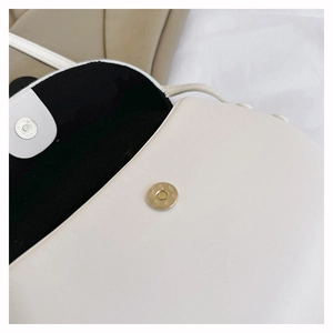 Detail of white leather shoulder bag featuring magnetic metal buckle and black lining