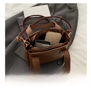 Detail view of brown pebbled leather bucket bag interior holding daily essentials