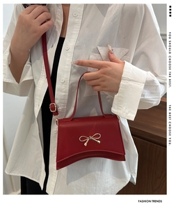 Détail du sac bandoulière bordeaux avec fermoir nœud doré et base incurvée élégante
