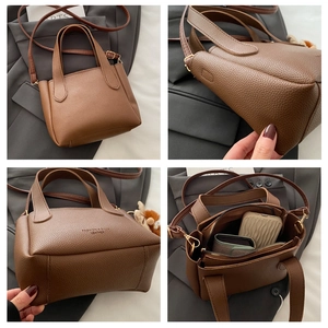 Detailed view of brown lychee grain leather bucket bag with handle and adjustable strap