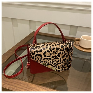 Détail du sac en cuir rouge avec rabat imprimé léopard et garniture en métal doré