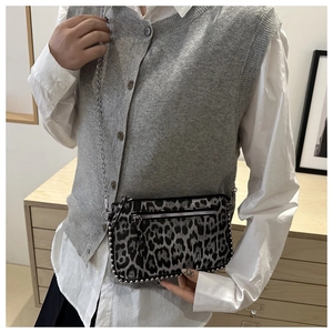 Fashionable mini leopard print crossbody bag with silver rivets on model's shoulder