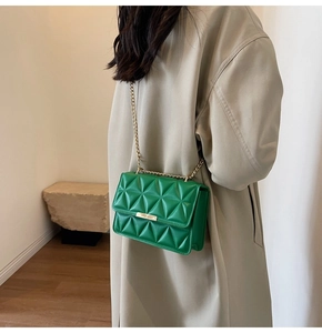 Detail of bright green quilted crossbody bag with gold chain strap on beige coat