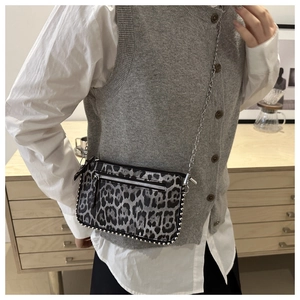 Detail of leopard print shoulder bag with silver studs and chain strap on a model
