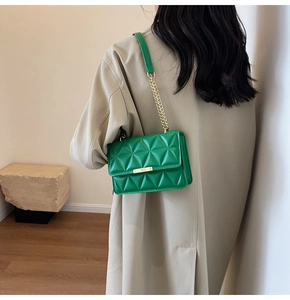 Detail of emerald green leather handbag featuring gold hardware and triangle quilting