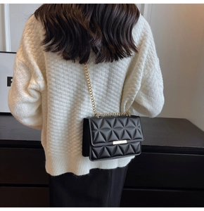 Detail of black quilted leather crossbody bag with golden chain and metallic lock