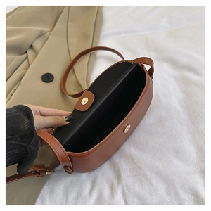 Detailed interior of brown matte leather saddle bag showing magnetic clasp and compartment