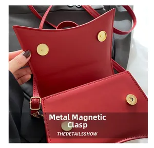 Vue détaillée du sac bandoulière rouge avec boucles magnétiques dorées et détails internes