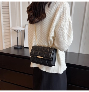 Chic black quilted crossbody bag with gold chain strap worn by a model in a minimal room