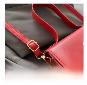 Détail du sac à bandoulière rouge avec boucle de réglage en métal doré et fermoir mousqueton