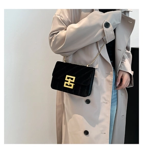 Détail du sac à bandoulière en velours noir avec boucle géométrique dorée et chaîne