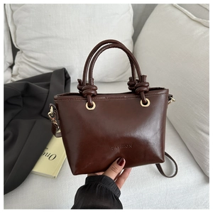 Vue détaillée d'un sac seau marron foncé brillant avec poignées nouées et anneaux