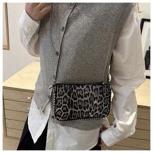 Detail of crossbody bag with grey leopard print, silver bead rivets and metal chain