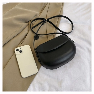Mini semi-circle matte black crossbody bag shown next to a phone for size reference
