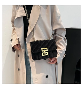 Détail du sac bandoulière en velours noir avec chaîne dorée et texture matelassée
