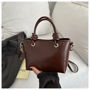 Détail du sac seau marron foncé avec poignée à nœud et gaufrage de mode chic