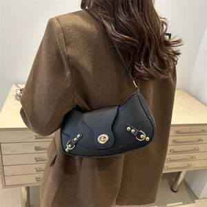 Chic black crescent underarm bag with gold studs shown on a model in wool blazer