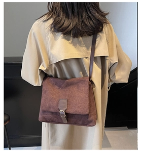 Detail of dark brown suede messenger bag worn with a khaki trench coat for a retro look