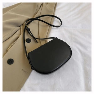 Detail of black saddle shoulder bag with gold buckle on a stylish khaki blazer jacket