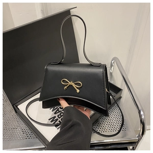 Detail of black bow-knot handbag with gold metallic hardware on minimalist display
