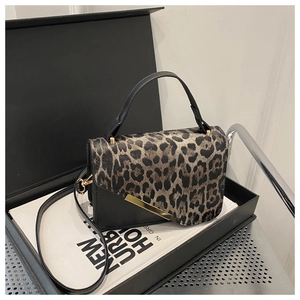 Détail du rabat léopard et boucle en métal doré sur un sac bandoulière en cuir noir