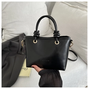 Détail du sac à main en cuir noir avec ferrures dorées et texture gaufrée FASHION