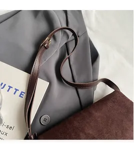 Detail of smooth leather shoulder strap and golden metal buckle on dark brown bag