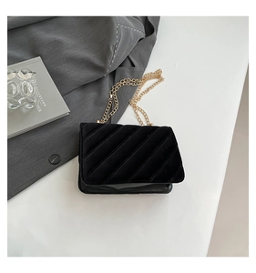Détail du sac bandoulière en velours noir avec motif matelassé et chaîne dorée