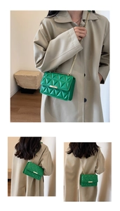 Detail of green quilted crossbody bag with gold chain strap and geometric stitch pattern