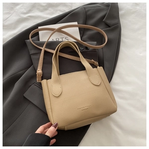 Dettaglio borsa a secchiello beige in pelle martellata con scritta e tracolla sottile